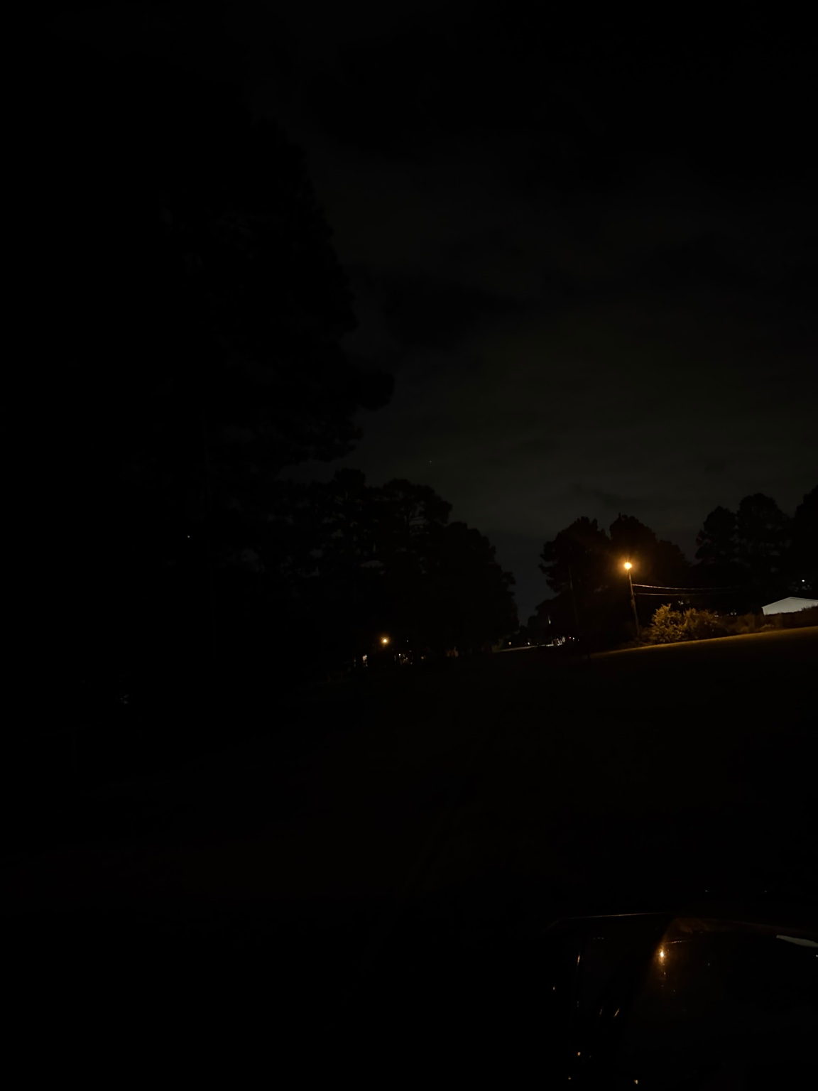 Dark residential road with one distant streetlight
