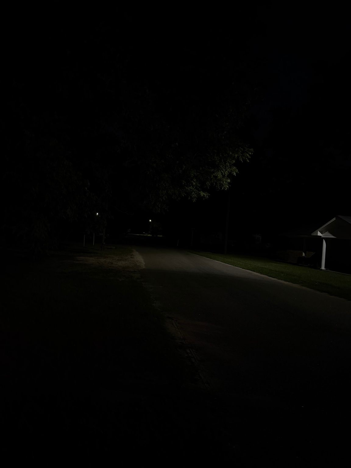 Dark neighborhood road with sparse lighting